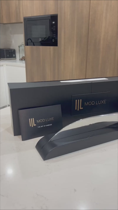 The SPLENDOUR Champagne Sabre by MOD LUXE – a personalised engraved stainless-steel champagne sabre and modern champagne sword for sabrage, elegantly presented on a wooden display with a luxury gift box. A masterpiece of design, craftsmanship, and celebration.