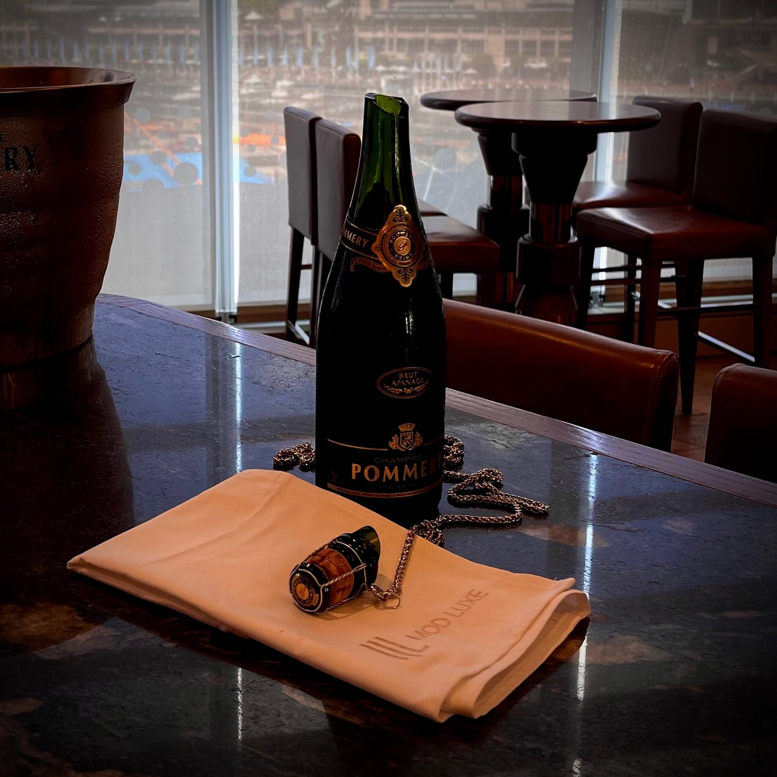 Cork and bottle top secured with a chain, displayed next to the champagne bottle after a sabrage strike, emphasising safety and environmental responsibility.